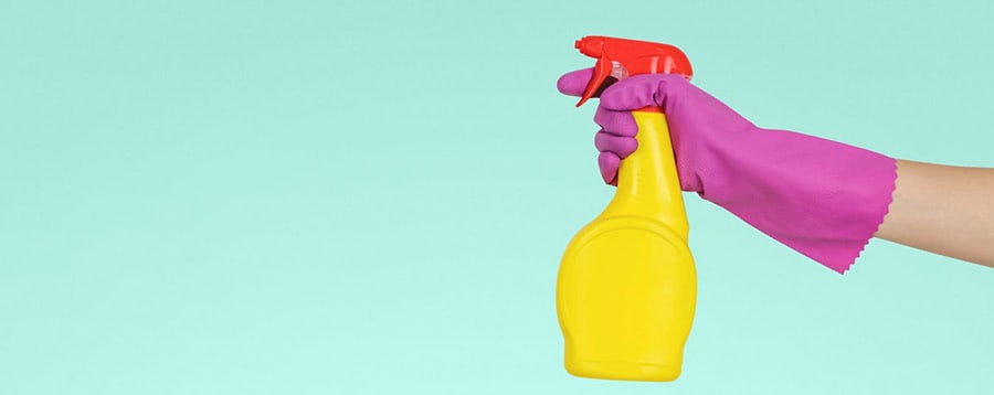 yellow spray bottle and pink rubber gloves