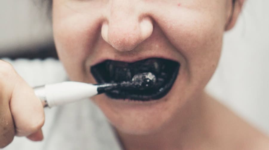 girl brushing teeth with charcoal