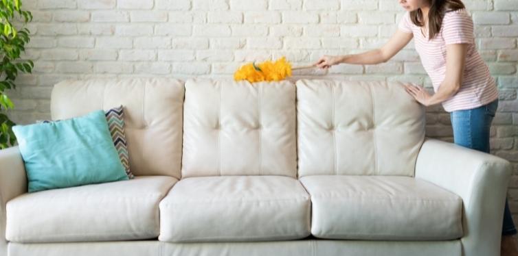 Woman removing dust from couch